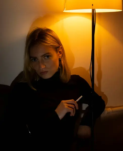 Geceleri odada sigara içen genç bir kadının portresi.