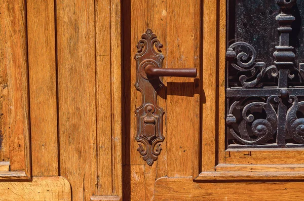 Part of vintage door. Wooden double door with wrought iron pattern and antique lock with handle.