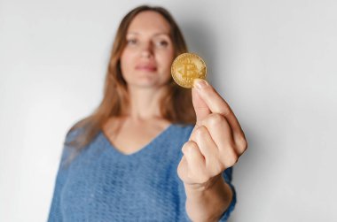 Günlük giysiler içindeki kadın portresi Bitcoin 'e bakıyor, gelecekteki para birimi, stüdyoda beyaz arka planda izole edilmiş. Halk yaşam tarzı konsepti
