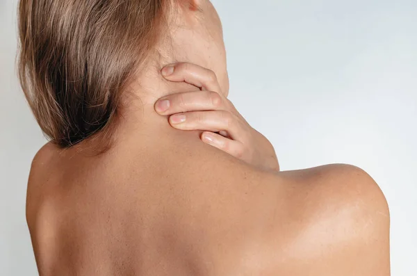 Massage for neck pain - woman with neck pain from behind, naked body