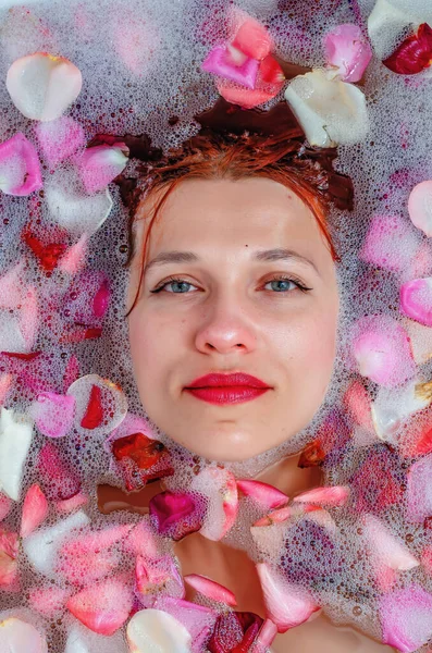 用柔和的白色 发亮的玫瑰花瓣把女性的脸贴在浴缸里 用于广告的复制空间 健美的概念 泡沫中的吸引性高加索模型 — 图库照片
