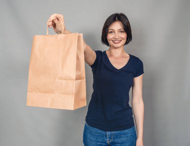 Güzel bir kadının portresi. Günlük giysiler giymişti. Kese kağıdıyla duruyor. Başarılı alışveriş.