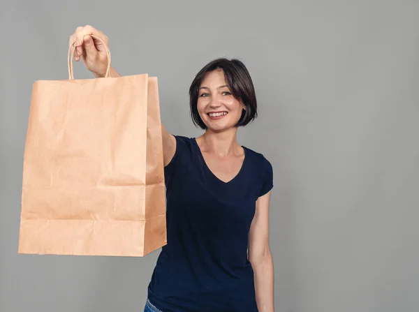 Portrait of  beautiful woman. Dressed in everyday clothes. Stands with a paper craft bag. Successful shopping.