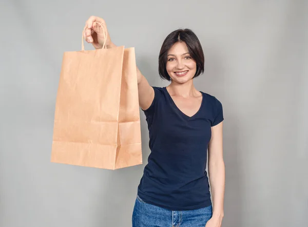 Portrait of  beautiful woman. Dressed in everyday clothes. Stands with a paper craft bag. Successful shopping.