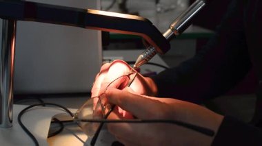 Eller gözlük için ince bir çerçeve kaynatıyor. Benek kaynaklama.