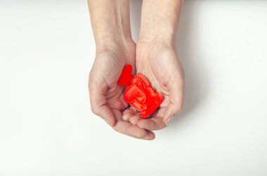 Female hands hold many small red hearts in their palms. White background
