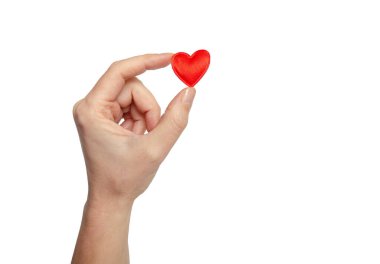 Female fingers hold tiny red heart. Symbol of love.