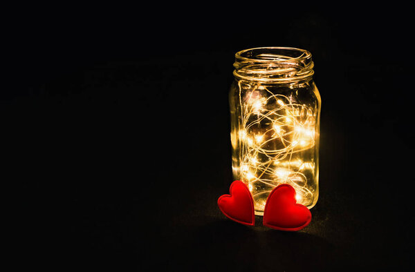 Warmth of two hearts. Atmospheric photo of glowing red hearts in glass. Black background