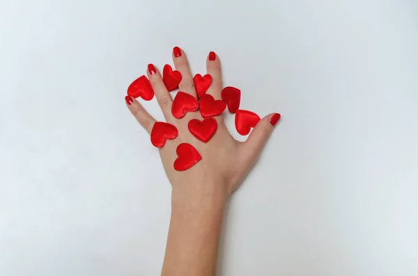 Female hand with red nails. Red hearts on hand. Manicure. Salon.