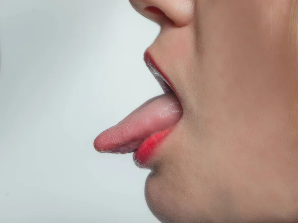 Side view of woman\'s mouth is open with tongue sticking out