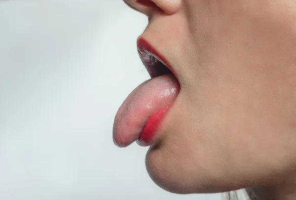 Side view of woman\'s face with her tongue sticking out. Treatment of ENT diseases.