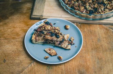 A piece of sweet cake with nuts, apples on blue plate