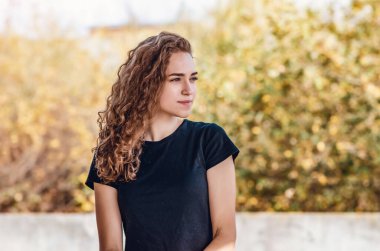 Side view of a charming young woman's face. Wavy hair, black T-shirt