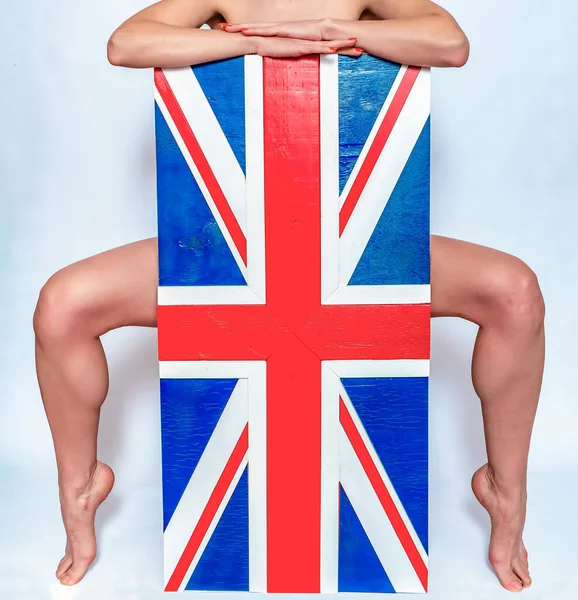 Flag of Great Britain. Naked female body hugs flag. Slender bare legs.