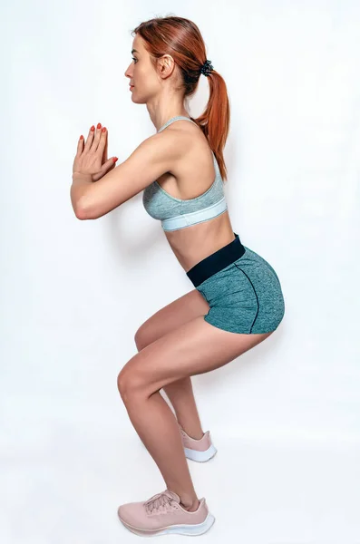 Slim woman doing squats. Side view. Fitness classes. Health benefits of squatting