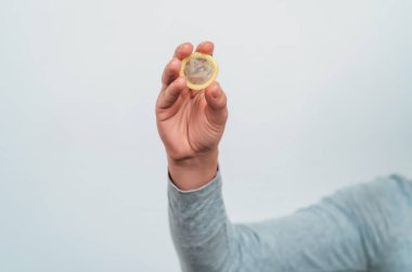 Kadının eli prezervatif tutuyor. Güvenli seks.