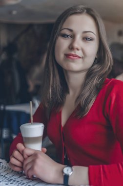 Cozy Cafe 'de bir fincan Latte içen mutlu ve rahat genç kadın.