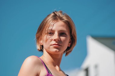 Mavi gökyüzüne karşı kısa saçlı genç kızın portresi