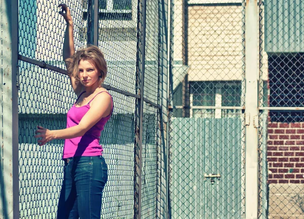 运动场金属栅栏旁的年轻女子 — 图库照片