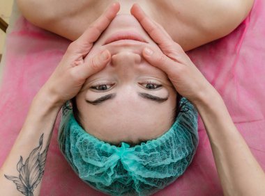 Yüz masajı. Kozmetik uzmanının elleri müşterinin çenesini okşar. Yüz bakımı