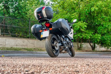 Şehirde yeşil ağaçların yanında duran ekstra gövdeli motosiklet.