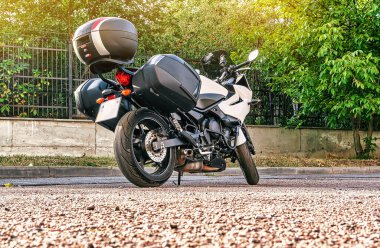 Şehirde yeşil ağaçların yanında duran ekstra gövdeli motosiklet.