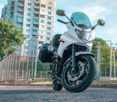 Beyaz motosiklet şehirde bir platformda duruyor.