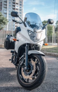 Beyaz motosiklet şehirde bir platformda duruyor.