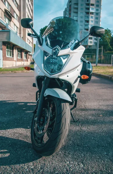 Beyaz motosiklet şehirde bir platformda duruyor.