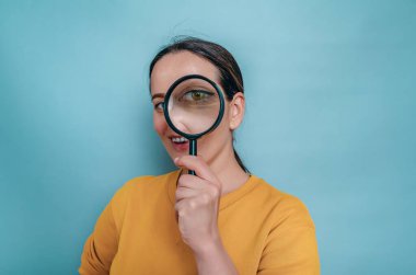 Gülümseyen kadın gözünün yanında büyüteç tutuyor. Araştırma, göz hastalıkları, tedavi.