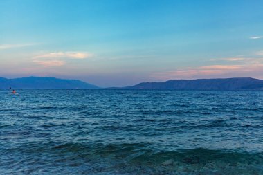 Sakin deniz manzarası. Açık gökyüzünün altında mavi deniz. Ufuktaki dağlar. Deniz dalgaları. Pozitif ekran koruyucu.