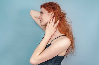 Kahverengi gözlü güzel bir kız profili. Bir el kızıl saçlara dokunur. Yakın çekim görünümü