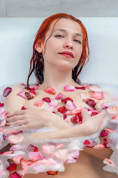 美しい女性は白い風呂に横たわって 水の上に花びらが上昇した リラクゼーション スパトリートメント — ストック写真