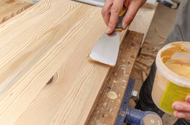 Marangoz ahşap bir tahtanın düğümlerini düzeltmek için macun kullanır. Kurtarma arkaplanı.