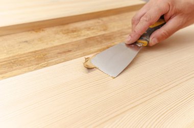 Tahtadaki düğümleri macunla kapatmak. Spatula, macun, tahta tahta. Marangozun elleri..