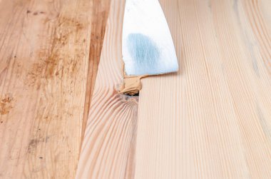 Marangoz ahşap bir tahtanın düğümlerini düzeltmek için macun kullanır. Kurtarma arkaplanı.