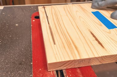 Tahtayı dairesel testere ile kesme işlemi. Marangozun eli eldivende.