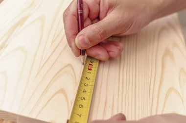 Marangozun eli tahta tahtaya kalem ile işaretleme yazar. Santimetre bandı