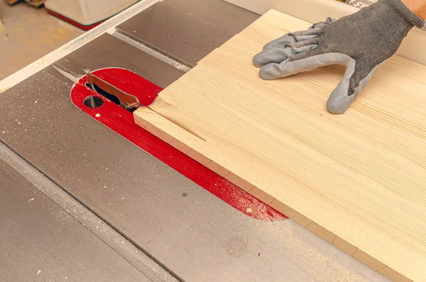 stock image Process of cutting wooden board with circular saw. Carpenter's hand in glove.