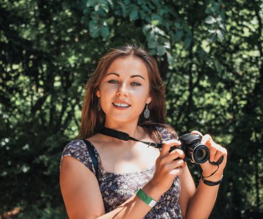 Elinde kamera olan sevimli bir kız doğada fotoğraf çekiyor..