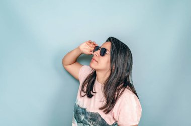 Siyah saçlı, güneş gözlüğü takan bir kadın. Yüze yakın el