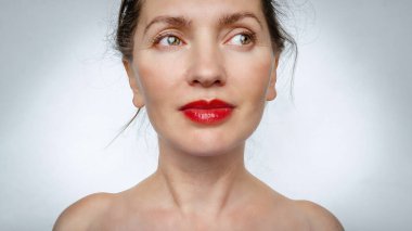 Geniş açıyla çekilmiş orta yaşlı bir kadının yakın plan portresi. Çıplak omuzlar.