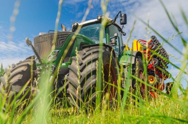 Yaratıcı tarım manzarası. Saha matkabıyla çimenlerin arasından traktöre alçak açı görünümü.