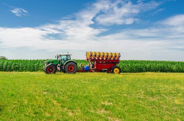 Tarımsal makineler araziyi boydan boya geçiyor. Büyük traktör. Görüntü daha iyi. Beyaz kümülüs bulutları arkaplan