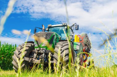Yaratıcı tarım manzarası. Saha matkabıyla çimenlerin arasından traktöre alçak açı görünümü.
