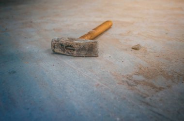 Tahta saplı eski bir çekiç beton zeminde yatıyor.