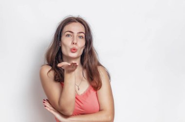 Hava öpücüğü hareketi. Tatlı bir kadın öpücük yolluyor. Koyu saçlı, pembe tişörtlü..