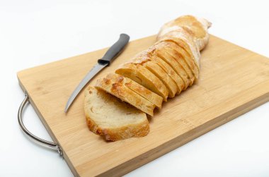 Slices of fresh bread and cutting knife on a wooden board. White background, isolated.