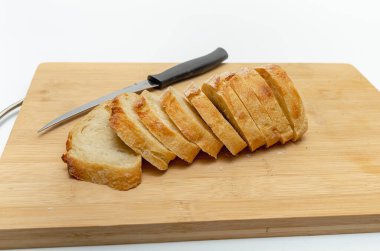 Slices of fresh bread and cutting knife on a wooden board. White background, isolated.