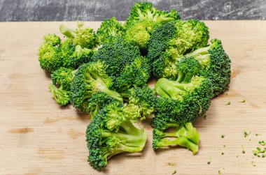 Tahta üzerinde çiçeklere ayrılmış taze yeşil brokoli. Sağlıklı beslenme için iştah açıcı sebze.